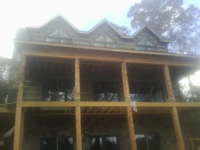 Dormers and porch framing on a large log home under construction — Roof Coating work by our crew in Pleasantville