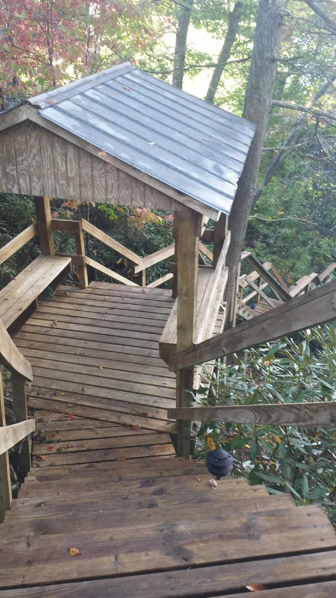 Metal roofed shelter over wooden steps on a wooded walkway — Skylight Repair & Installation work by our crew in Pleasantville