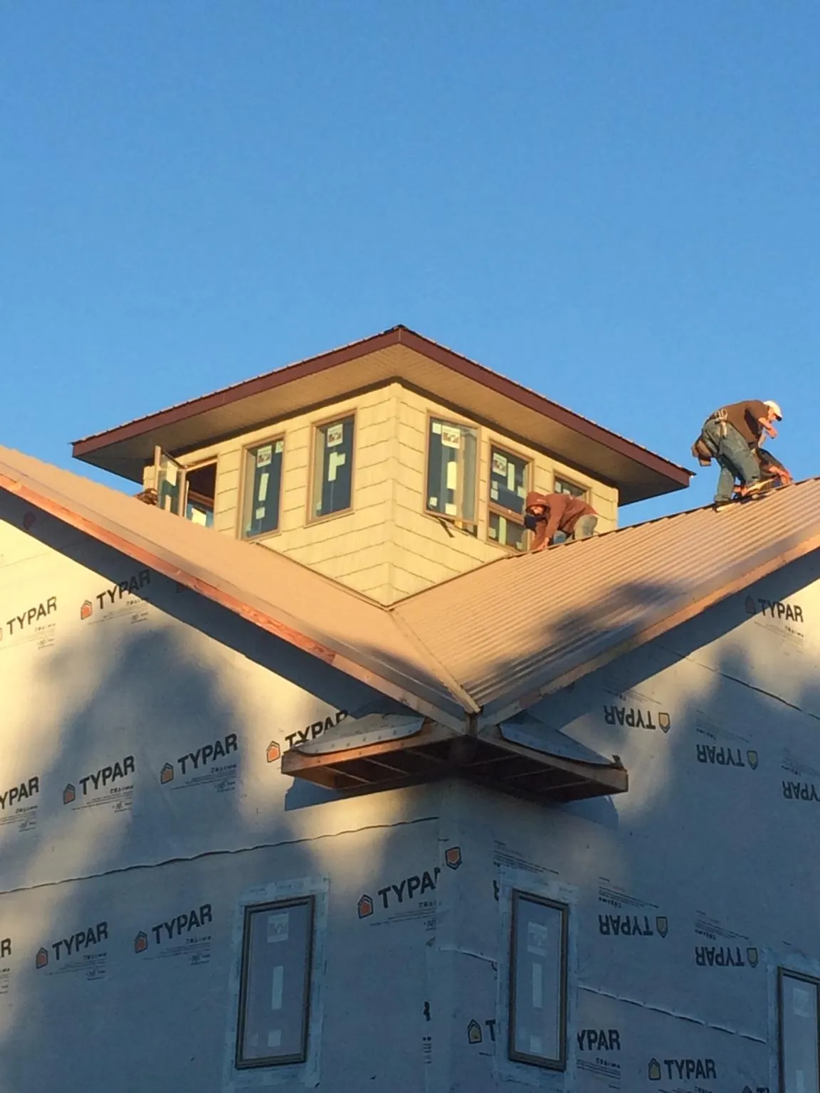 Roofers working around a rooftop cupola on a new metal roof at sunset — Roof Waterproofing in Pleasantville by Roofing Brothers